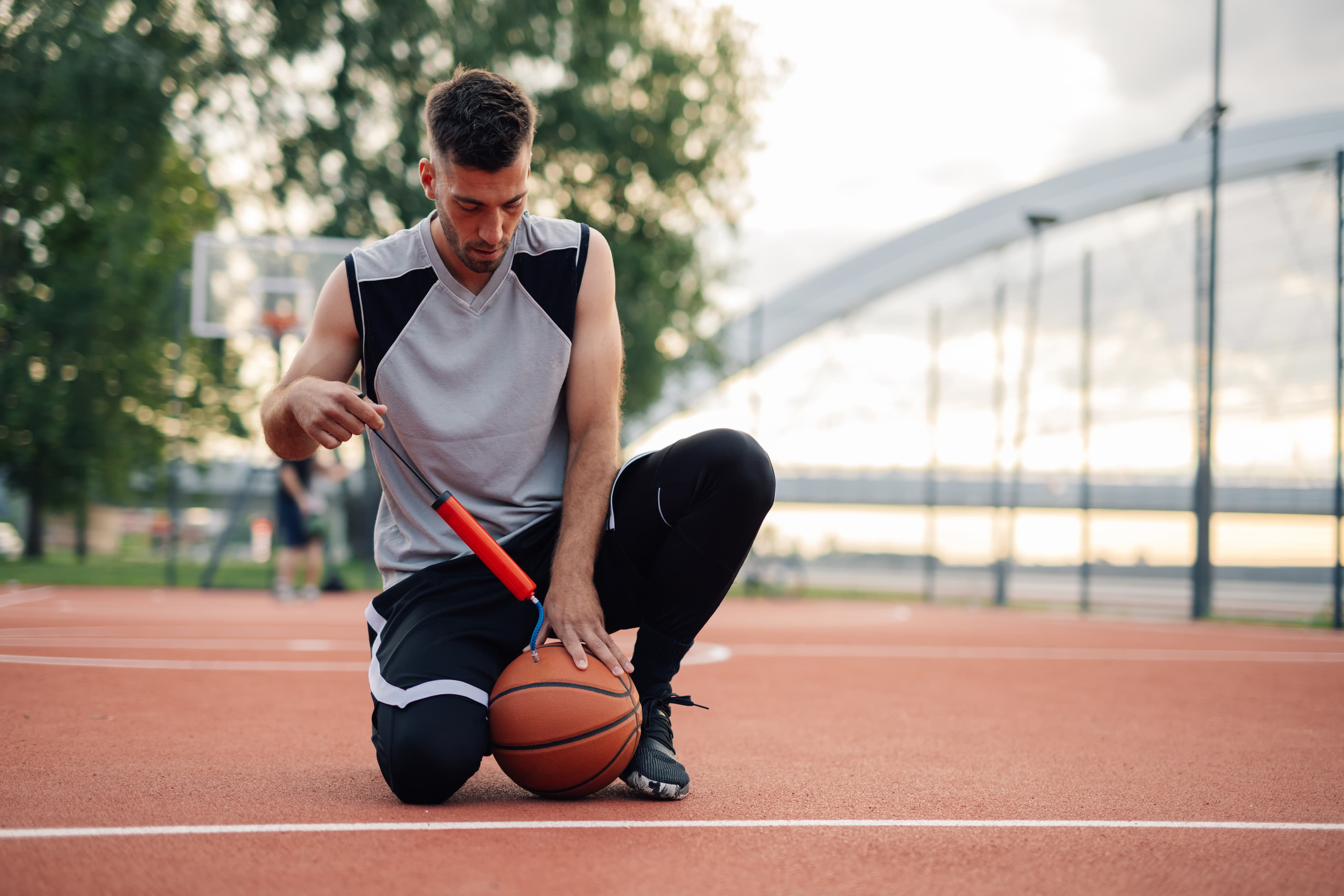 Athlete inflating a basketball on an outdoor court